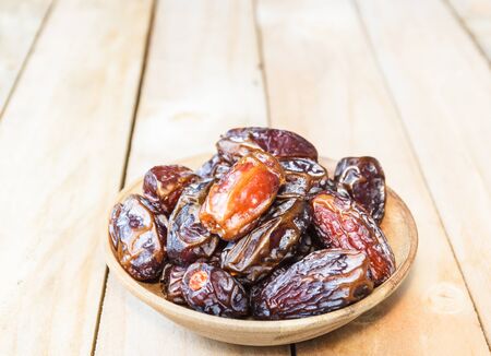 Dates fruit in a wooden bowl closeup on wooden backgroundの写真素材