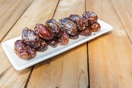 Dates fruit in a wooden bowl closeup on wooden backgroundの写真素材