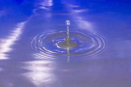 Water drop falling into water making a perfect droplet splashの写真素材