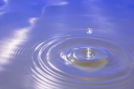 Water drop falling into water making a perfect droplet splashの写真素材