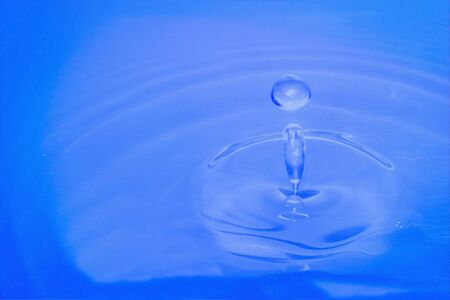 Water drop falling into water making a perfect droplet splashの写真素材