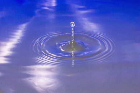 Water drop falling into water making a perfect droplet splashの写真素材