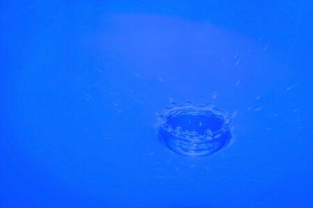 Water drop falling into water making a perfect droplet splashの写真素材