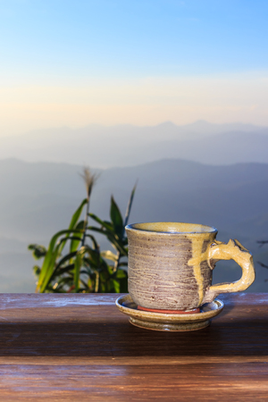 Cup with tea on table over mountains landscape with sunlight. Beauty nature background.の写真素材