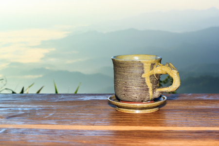 Cup with tea on table over mountains landscape with sunlight. Beauty nature background.の写真素材