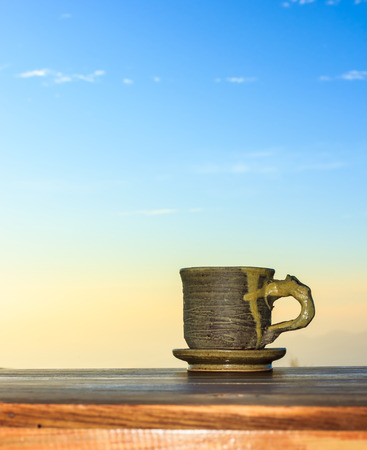 Cup of coffee on a wooden table in morning over mountain.の写真素材