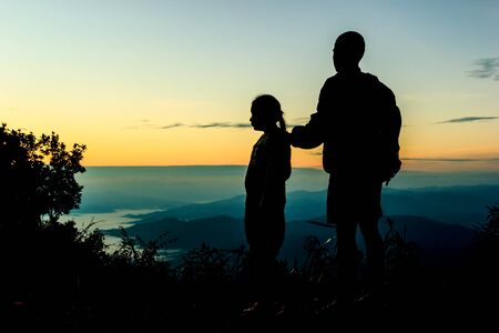 Boy with his sister on sunrise background.Silhouetteの写真素材