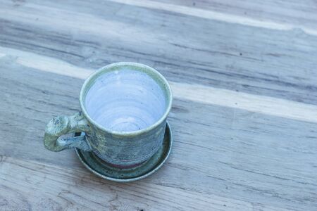 Cup of coffee on a wooden table in morning over mountain.の写真素材