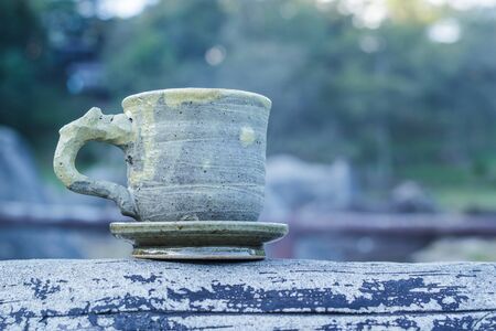 Cup of coffee on a wooden table in morning over mountain.の写真素材