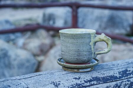 Cup of coffee on a wooden table in morning over mountain.の写真素材