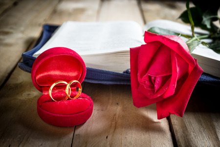 Red roses and wedding rings  on wooden backgroundの写真素材