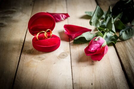 Red roses and wedding rings  on wooden backgroundの写真素材