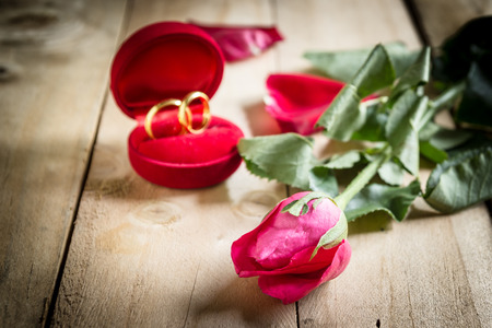 Red roses and wedding rings  on wooden backgroundの写真素材