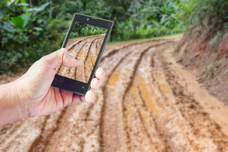 Business conceptual- Focused on left hand holding mobile with Trekking nature blurred backgroundの写真素材