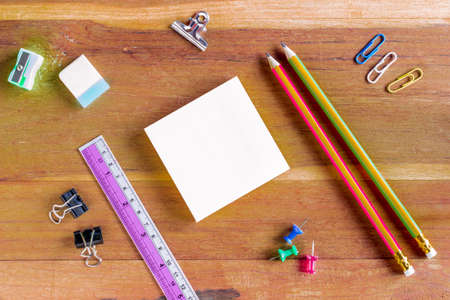 Assorted Office Supplies on Wooden Table, Emphasizing White Blank Notepad at the Center with Copy Space for Texts.の写真素材