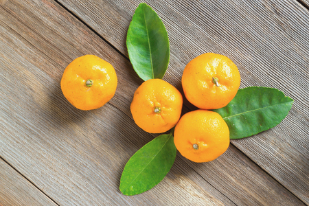 fresh mandarins in wooden bowl with leafs on old wooden tableの写真素材