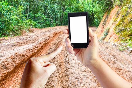 Business conceptual- Focused on left hand holding empty mobile with Trekking dirt road blurred backgroundの写真素材