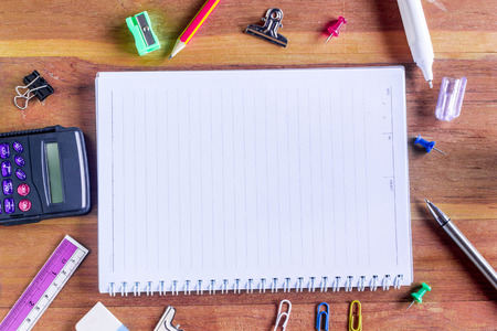 Assorted Office Supplies on Wooden Table, Emphasizing White Blank Notepad at the Center with Copy Space for Texts.の写真素材