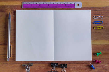 Assorted Office Supplies on Wooden Table, Emphasizing White Blank Notepad at the Center with Copy Space for Texts.の写真素材