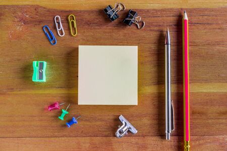 Assorted Office Supplies on Wooden Table, Emphasizing White Blank Notepad at the Center with Copy Space for Texts.の写真素材