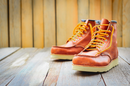 A pair of brown leather boots with laces placed on wooden floor, selective focusの写真素材