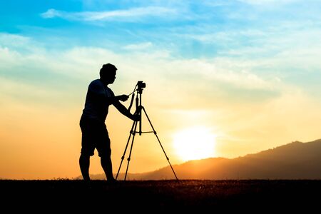 Silhouette of a young photographer during the sunset.の写真素材