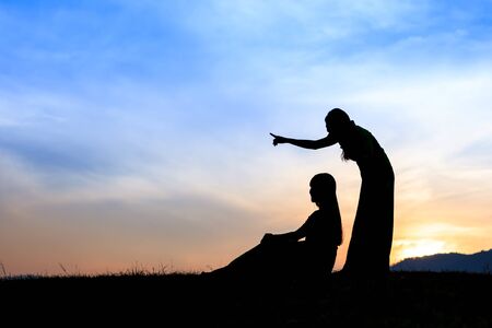 Silhouette happy girls on a meadow at sunsetの写真素材