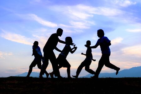 Children playing on summer sunset meadowの写真素材