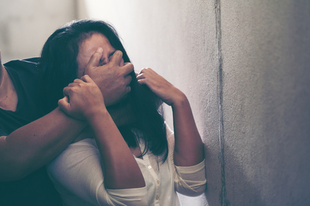 Sexual abuse with a man attacking to a scared woman in a dark placeの写真素材