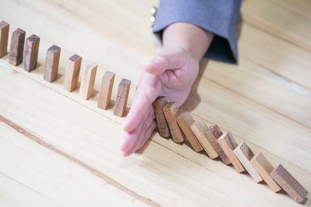 Images of hand stopping domino effect with his finger. Business crisis concept.の写真素材