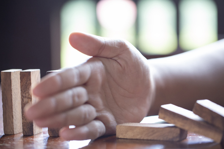 Businessman stopping domino effect with his finger. Business crisis concept.の写真素材
