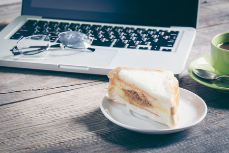Office desk and simple concept business marketing plan notes have blank book, silver pencil, mobile phone, black coffee, sandwich is elements with copy spaceの写真素材