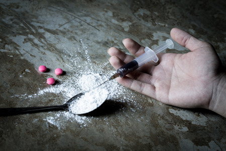 International Day against Drug Abuse. Young human hand trying to reach cooked heroin spoon on grungy concrete floor. Drugs addiction and withdrawal symptoms concept. Copy space.の写真素材