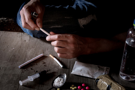 Man makes heroin, preparing to take heroin, pours heroin into a spoon. The concept of crime and drug addiction.の写真素材