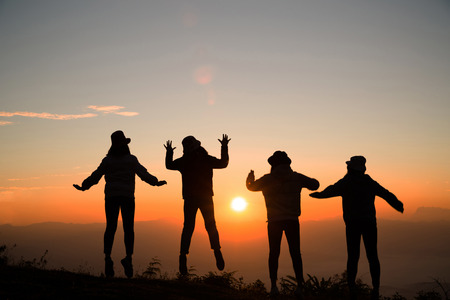 Silhouette of young woman are standing on top of the mountain relaxing with sunrise by nature at...