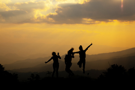 Group of happy people jumping in the mountain at sunset, concept about having fun on the hill, silhouetteの写真素材