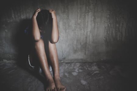 Little sad girl hiding or locked in the basement. trafficked and abusedの写真素材