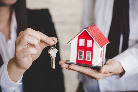 Young lady taking keys from female real estate agent during meeting after signing rental lease contract or sale purchase agreement.の写真素材