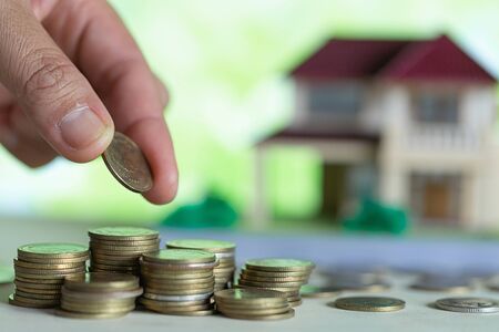 House placed on coins female hand is planning savings money of coins to buy a home, saving money for...