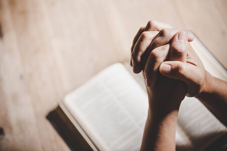Spirituality and religion, Hands folded in prayer on a Holy Bible in church concept for faith.の写真素材