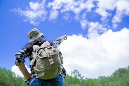 Travelers, young women, look at the amazing mountains and forests, wanderlust travel ideas, space for messages, great moments of the atmosphere.の写真素材