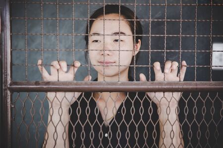 beautiful young girl behind the bars, prisoner concept.の写真素材