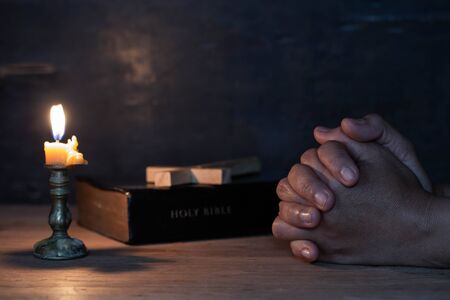 The woman's hand prayed with the scripture and  the candle on the wooden tableの写真素材