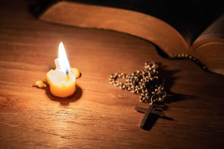 Bible, wood Cross and candles on an old wooden table with a dark backgroundの写真素材