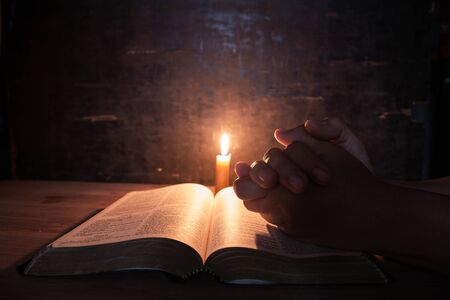 women praying on the Bible in the light candles selective focus. Beautiful gold background. Religion...