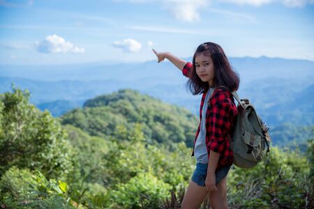 Travelers, young women, look at the amazing mountains and forests, wanderlust travel ideas, space for messages, great moments of the atmosphere.の写真素材