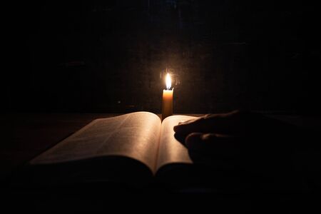 women praying on the Bible in the light candles selective focus. Beautiful gold background. Religion concept.の写真素材