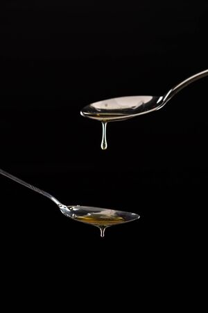 golden sweet honey dripping from spoon anthracite isolatedの写真素材