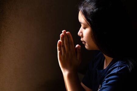 Portrait of a cute girl praying with her eyes closed
