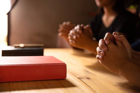 Christian people prays together around wooden table with bible.の写真素材